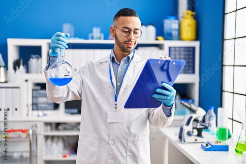 African american man scientist  holding test tube reading document at laboratory