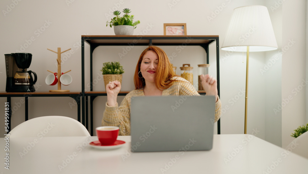 Young redhead woman using laptop with celebrate expression at home Young redhead woman using laptop with celebrate expression at home