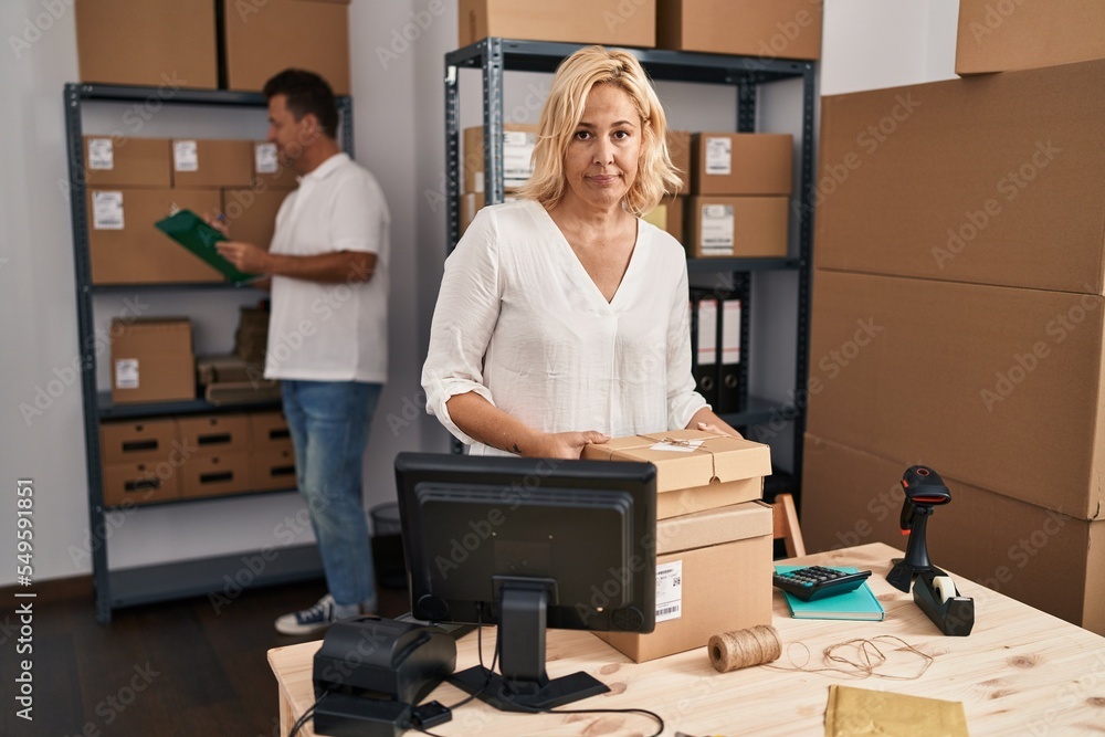 Middle age woman and man working at small business ecommerce thinking attitude and sober expression looking self confident Middle age woman and man working at small business ecommerce thinking attitude and sober expression looking self confident