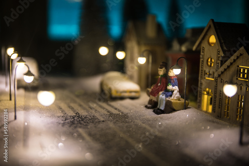 Fototapeta Naklejka Na Ścianę i Meble -  Little decorative cute small houses in snow at night in winter, Christmas and New Year miniature house in the snow at night with fir tree. Holiday concept.