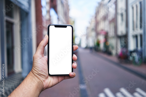 Man holding smartphone showing white blank screen at amsterdam