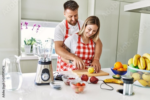 Young couple smiling confident making smoothie hugging each other at kitchen