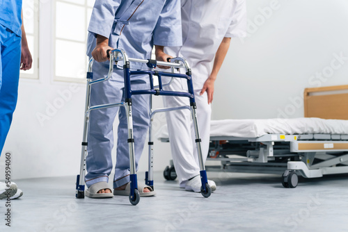 歩行器を使ってリハビリする患者とケアスタッフ © metamorworks