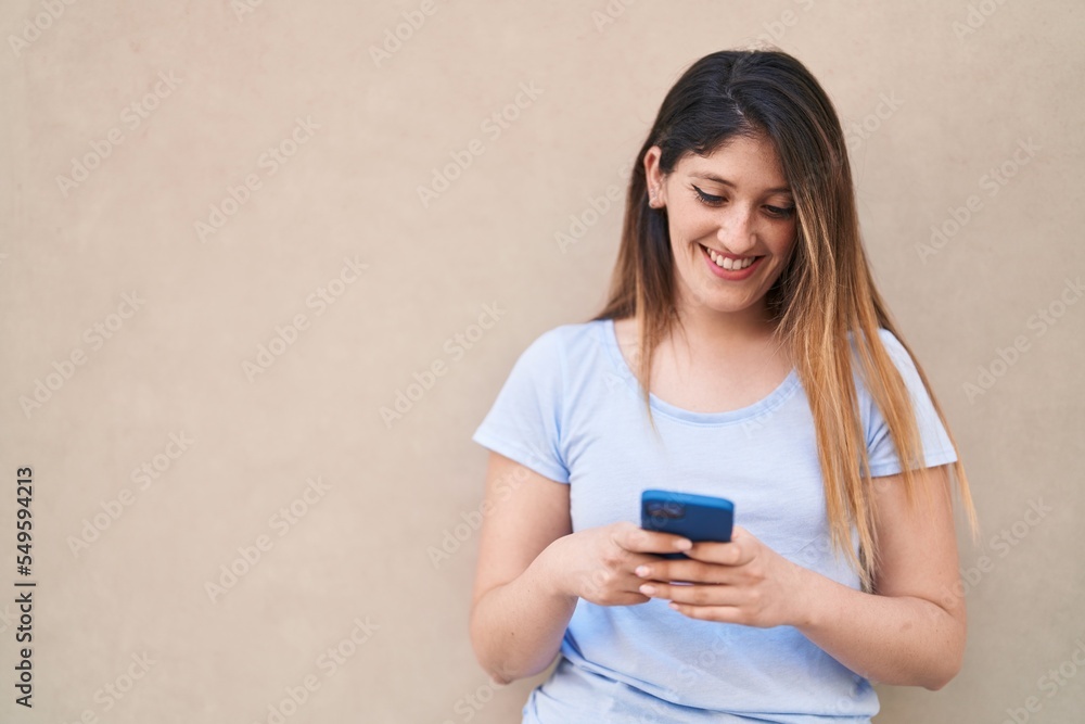 Young hispanic woman smiling confident using smartphone over isolated white background Young hispanic woman smiling confident using smartphone over isolated white background