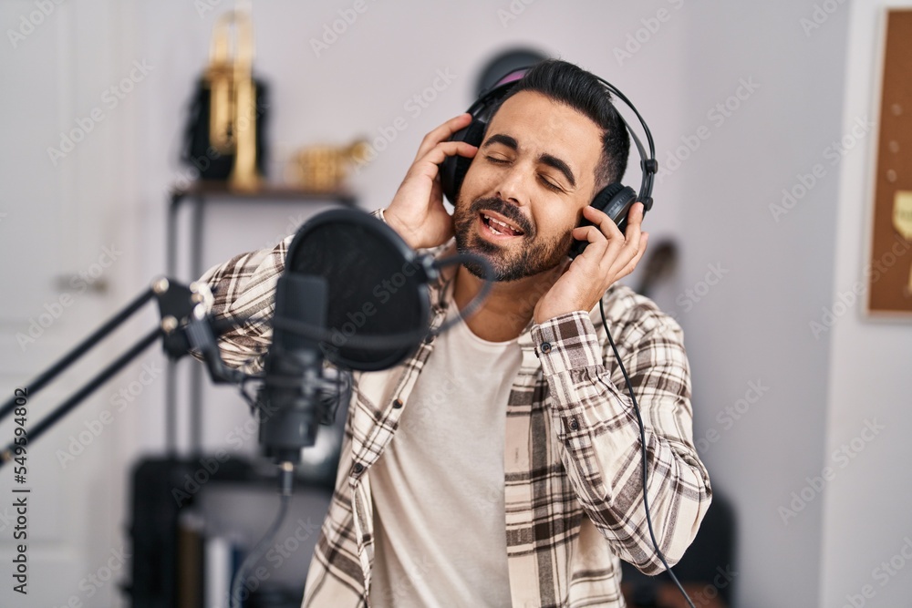 Young hispanic man artist singing song at music studio Young hispanic man artist singing song at music studio