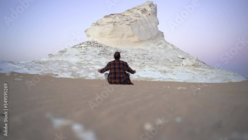 White Desert National Park Egypt young traveller caucasian sit-in gin front of the sunset contemplating the beauty of Mother Earth
