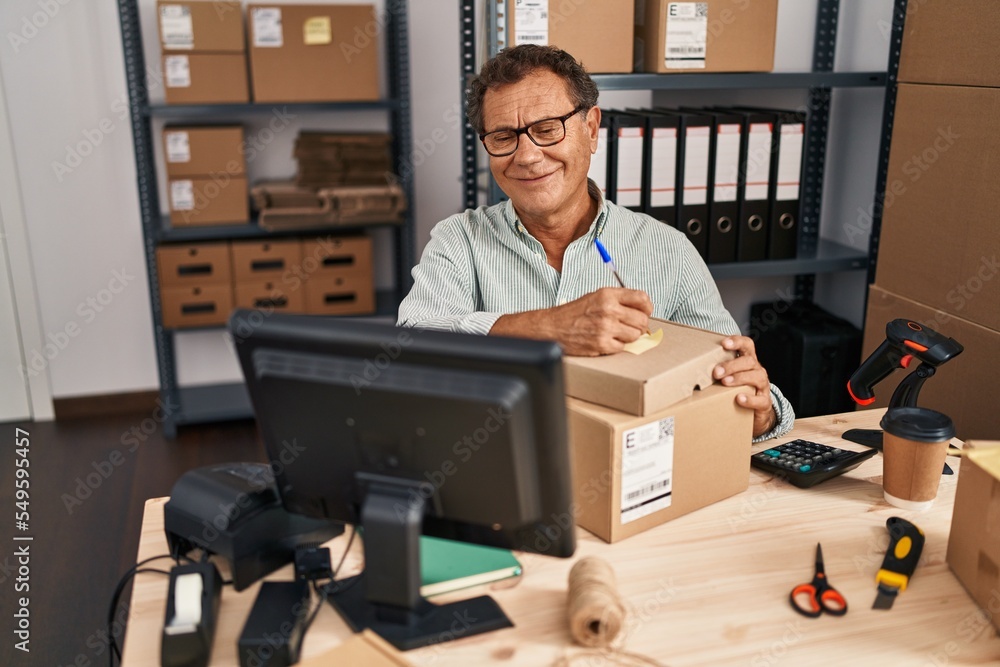 Middle age man ecommerce business worker writing on package at office