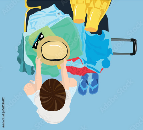 Little boy unpacking suitcase for vacation on blue background, top view