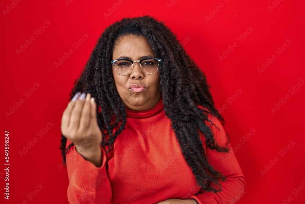 Plus size hispanic woman standing over red background doing italian gesture with hand and fingers confident expression Plus size hispanic woman standing over red background doing italian gesture with hand and fingers confident expression