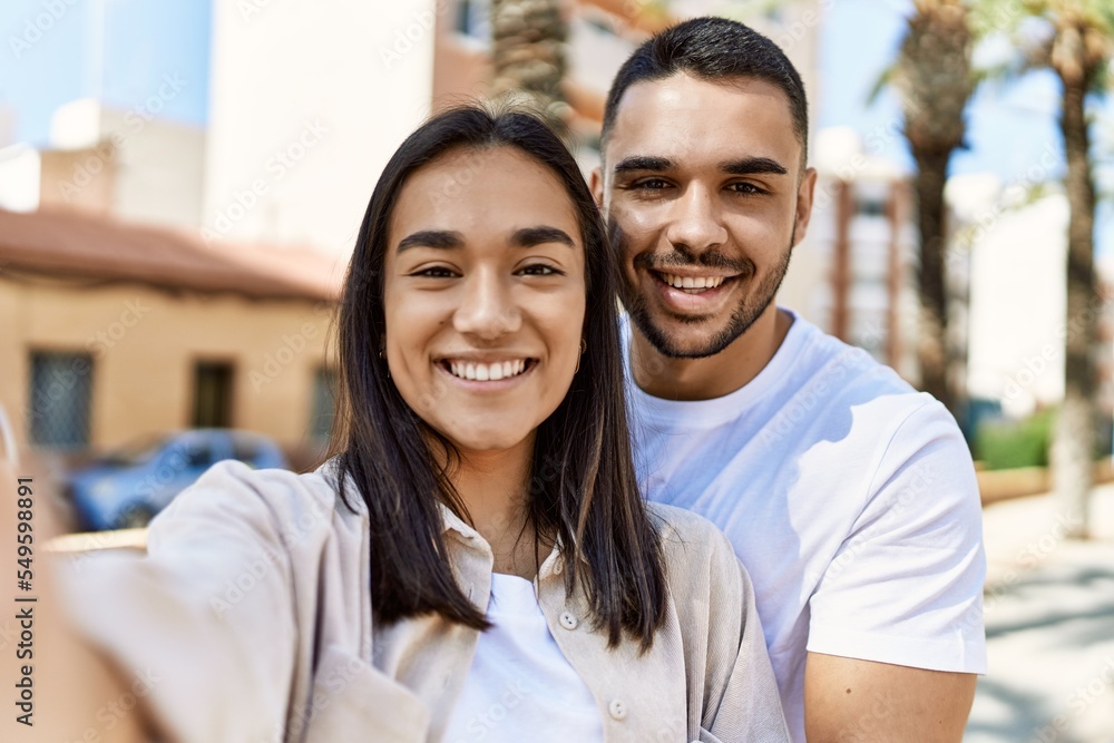 Young latin couple smiling happy and hugging making selfie by the camera at the city. Young latin couple smiling happy and hugging making selfie by the camera at the city.