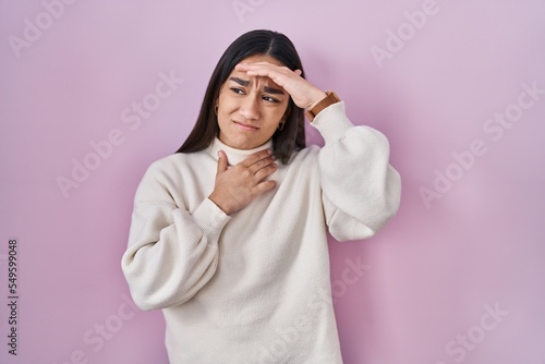 Young south asian woman standing over pink background touching forehead for illness and fever, flu and cold, virus sick © Krakenimages.com