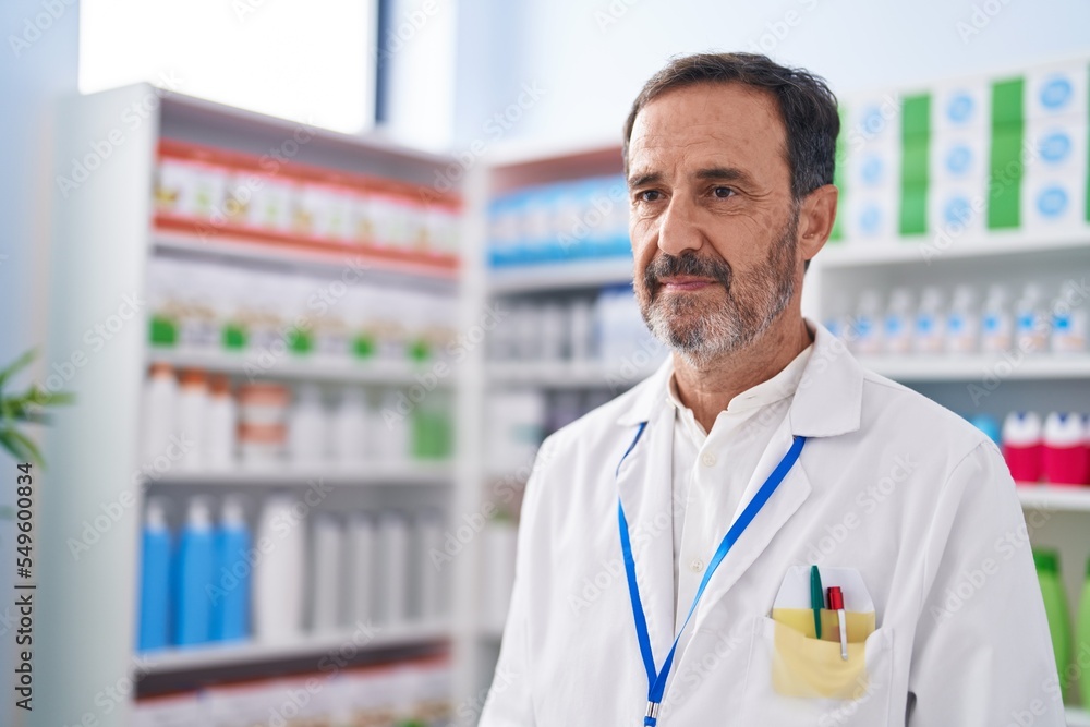 Middle age man pharmacist standing with relaxed expression at pharmacy Middle age man pharmacist standing with relaxed expression at pharmacy