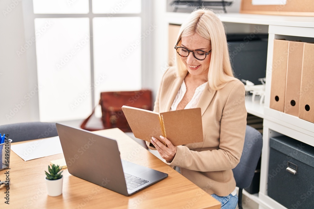 Young blonde woman business worker writing on notebook working at office Young blonde woman business worker writing on notebook working at office