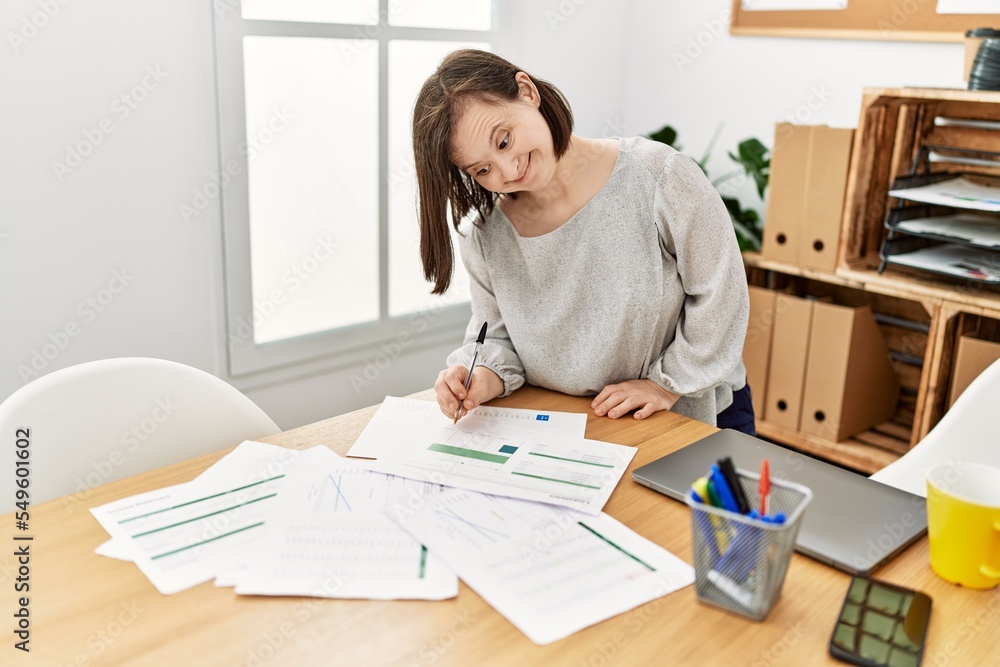 Brunette woman with down syndrome working with documents at business office Brunette woman with down syndrome working with documents at business office