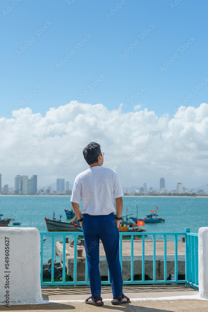 man traveler visiting at Son Tra marina. Tourist with blue dress and hat traveling in Da Nang city. Vietnam and Southeast Asia travel concept man traveler visiting at Son Tra marina. Tourist with blue dress and hat traveling in Da Nang city. Vietnam and Southeast Asia travel concept
