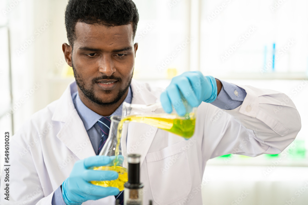 Happy male scientist working in lab. Smiling Scientist woman with yellow liquid in a researcher test tube. Happy male scientist working in lab. Smiling Scientist woman with yellow liquid in a researcher test tube.