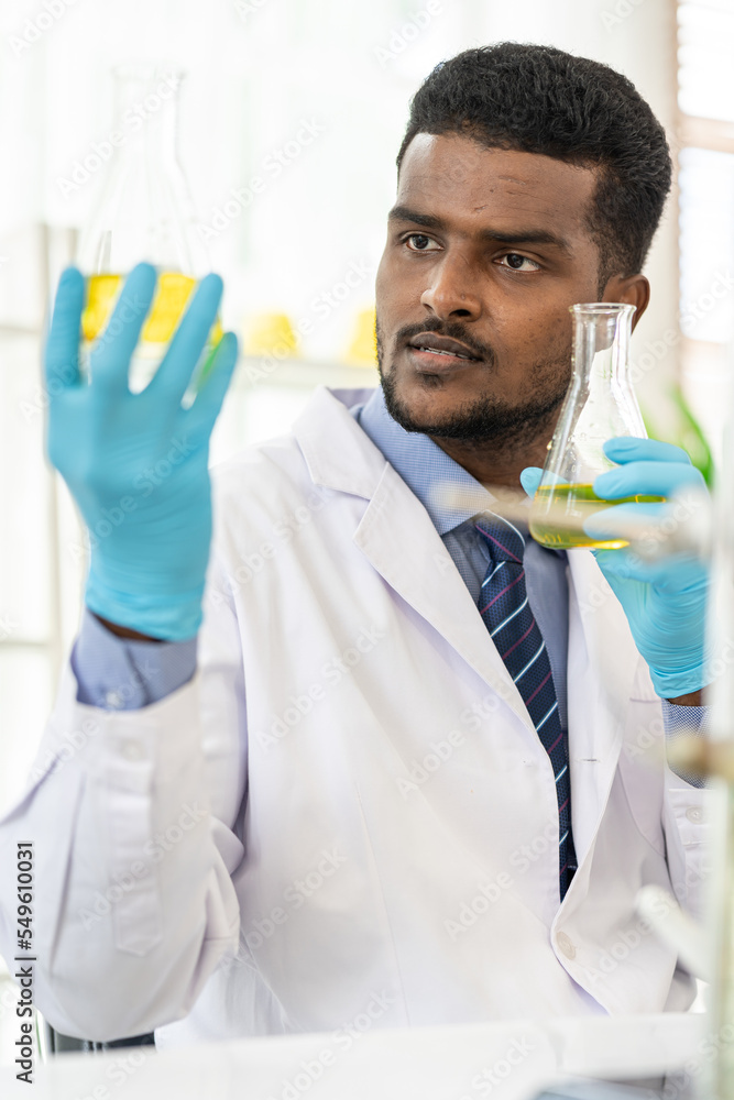 Happy male scientist working in lab. Smiling Scientist woman with yellow liquid in a researcher test tube. Happy male scientist working in lab. Smiling Scientist woman with yellow liquid in a researcher test tube.