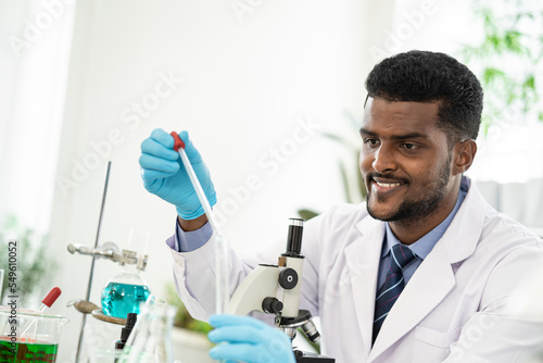 Happy male scientist working in lab. Smiling Scientist woman with yellow liquid in a researcher test tube.
