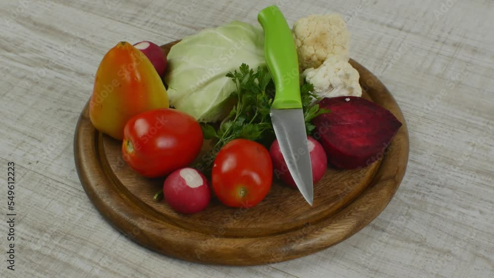 Beautifully stacked fresh salad vegetables on a round brown wooden cutting board. Vegetarianism, veganism, raw food healthy lifestyle. Healthy eating and longevity. Environmentally friendly products Beautifully stacked fresh salad vegetables on a round brown wooden cutting board. Vegetarianism, veganism, raw food healthy lifestyle. Healthy eating and longevity. Environmentally friendly products