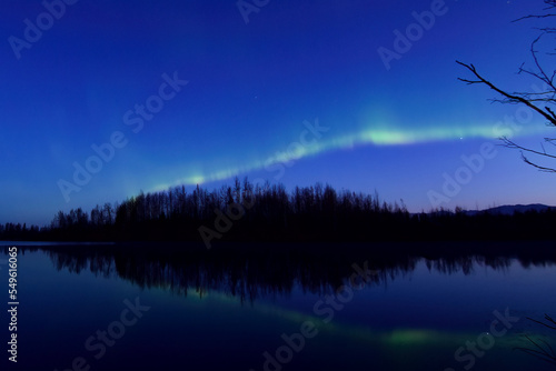 A band of aurora borealis shines over Reflections Lake, Alaska, just before dawn on a cold winter morning. © JT Fisherman