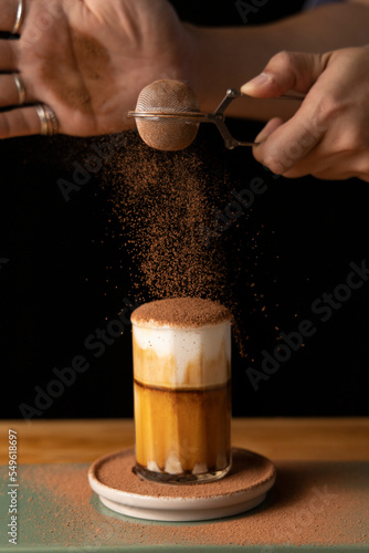 Selective focus Close up made mocha latte or chocolate coffee , Hand sprinkled chocolate powder on glass.