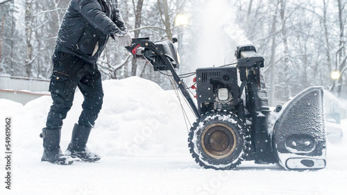 a janitor on a snowplow removes snow in the courtyard of a residential building