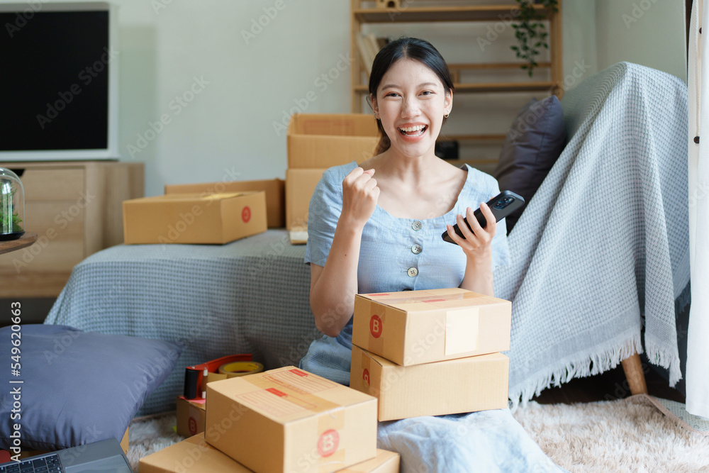 Starting small business entrepreneur of independent Asian woman smiling using computer laptop with cheerful success of online marketing package box items and SME delivery concept Starting small business entrepreneur of independent Asian woman smiling using computer laptop with cheerful success of online marketing package box items and SME delivery concept