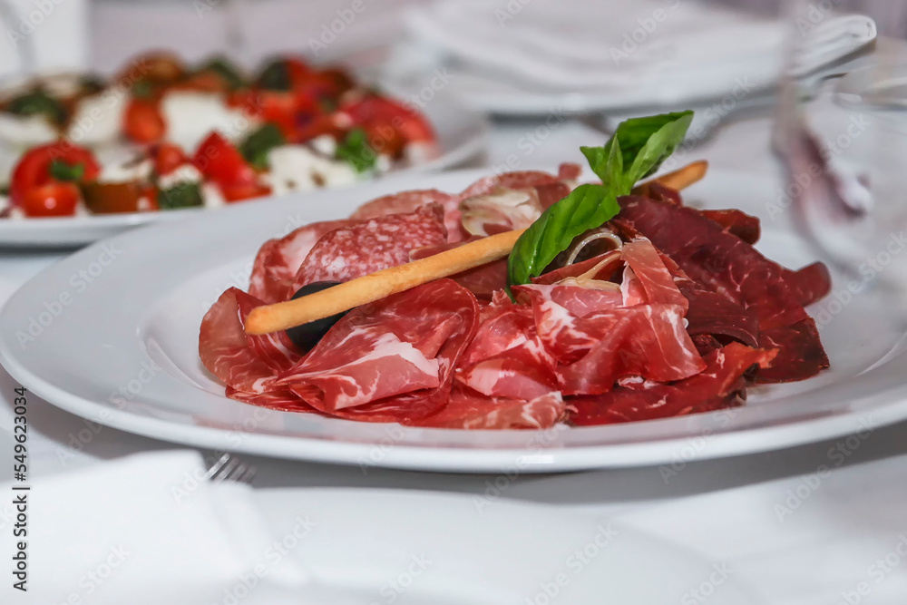 Carpaccio on a plate on a festive table with a white tablecloth. Appetizing cold appetizers. Close-up.