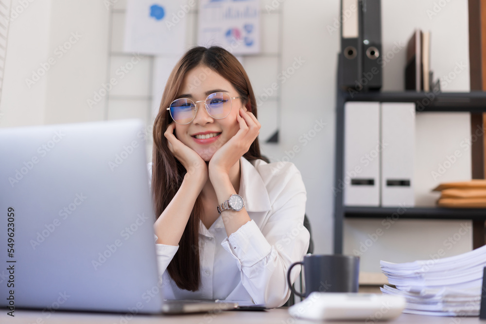 Business concept, Businesswoman is touching chin on hands and reading business data on laptop Business concept, Businesswoman is touching chin on hands and reading business data on laptop