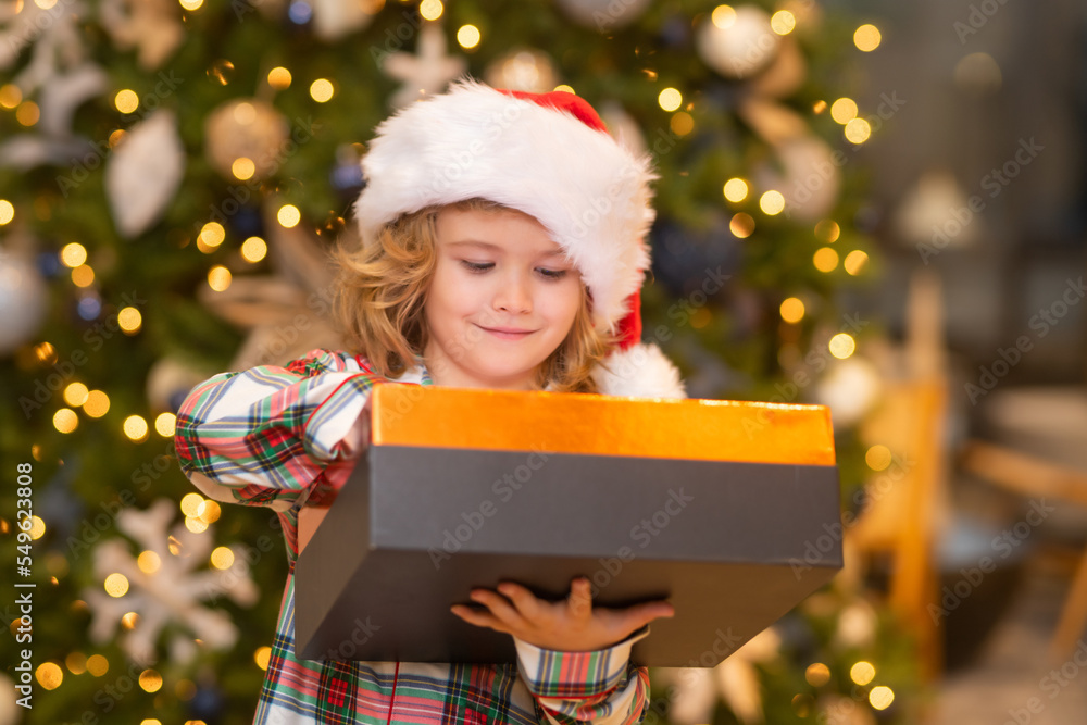 Kid boy in santa hat near christmas tree at home. Kid boy in santa hat near christmas tree at home.