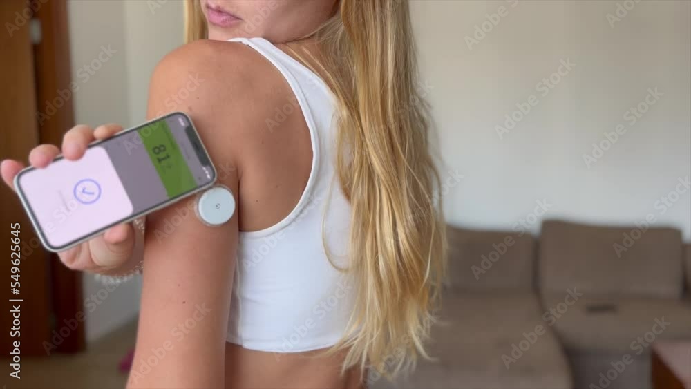 Woman checking blood sugar level with the glucometer device on her shoulder with an app Woman checking blood sugar level with the glucometer device on her shoulder with an app