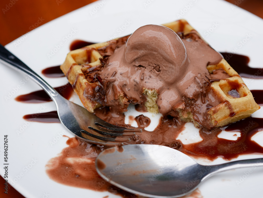Chocolate waffle already sliced with ice cream topping on a plate