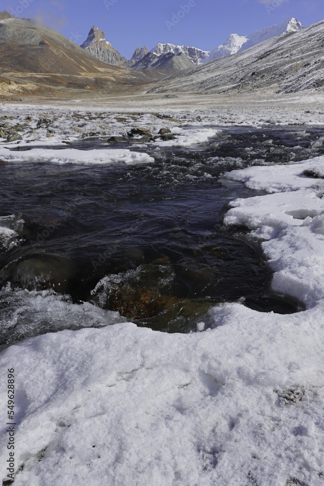 frozen mountain stream flowing through the scenic alpine valley at yumesodong or zero point, the beautiful himalayan valley located in north sikkim, india frozen mountain stream flowing through the scenic alpine valley at yumesodong or zero point, the beautiful himalayan valley located in north sikkim, india