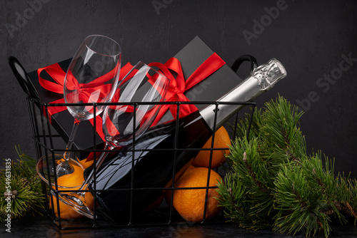 Fototapeta Naklejka Na Ścianę i Meble -  Basket with Christmas gift boxes, champagne, oranges