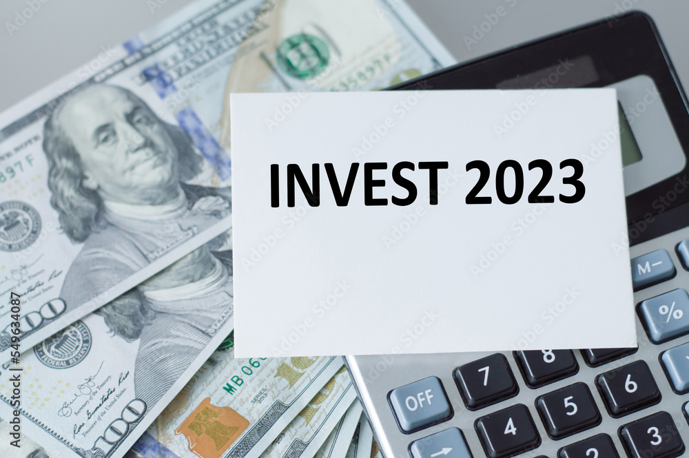 Invest 2023 text on a card, calculator and dollors Invest 2023 text on a card, calculator and dollors