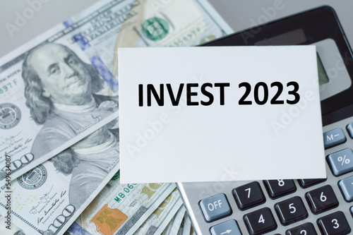 Invest 2023 text on a card, calculator and dollors