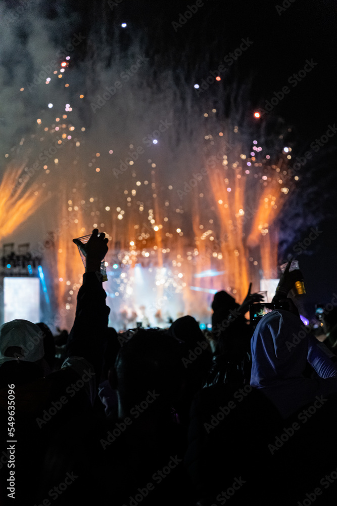 Fototapeta premium silhouette of people enjoying an outdoor concert at night with fireworks.