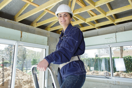 Billede på lærred young woman builder stands on a stepladder