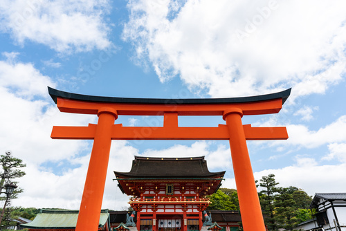 front view of giant vermillion torii entrance gate and the romon gate of Fushimi Inari Taisha shrine on a sunny day in spring