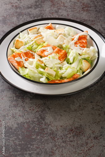 Salmon Caesar Salad it features easy homemade dressing, freshly baked croutons, parmesan and grilled salmon closeup on the plate on the table. Vertical