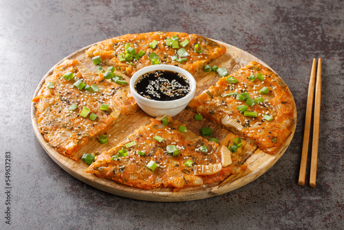 Kimchijeon is a Korean savory crispy pancake made of kimchi with flour and onion closeup on the wooden board on the table. Horizontal