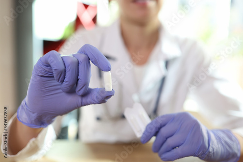 Doctor proctologist holding in his hands antiinflammatory suppository for hemorrhoids closeup photo