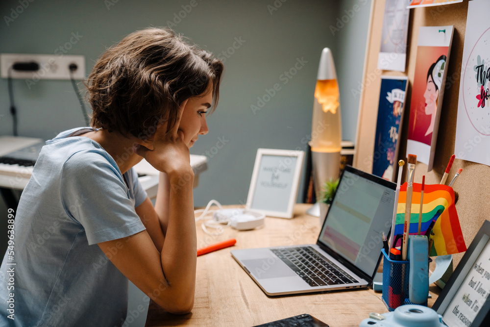 Fototapeta premium Young white woman working with laptop while sitting at desk