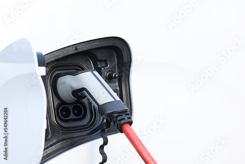 Power cable pump plug in charging power to electric vehicle EV car with modern technology UI control information display, car fueling station connected power cable alternative sustainable eco energy