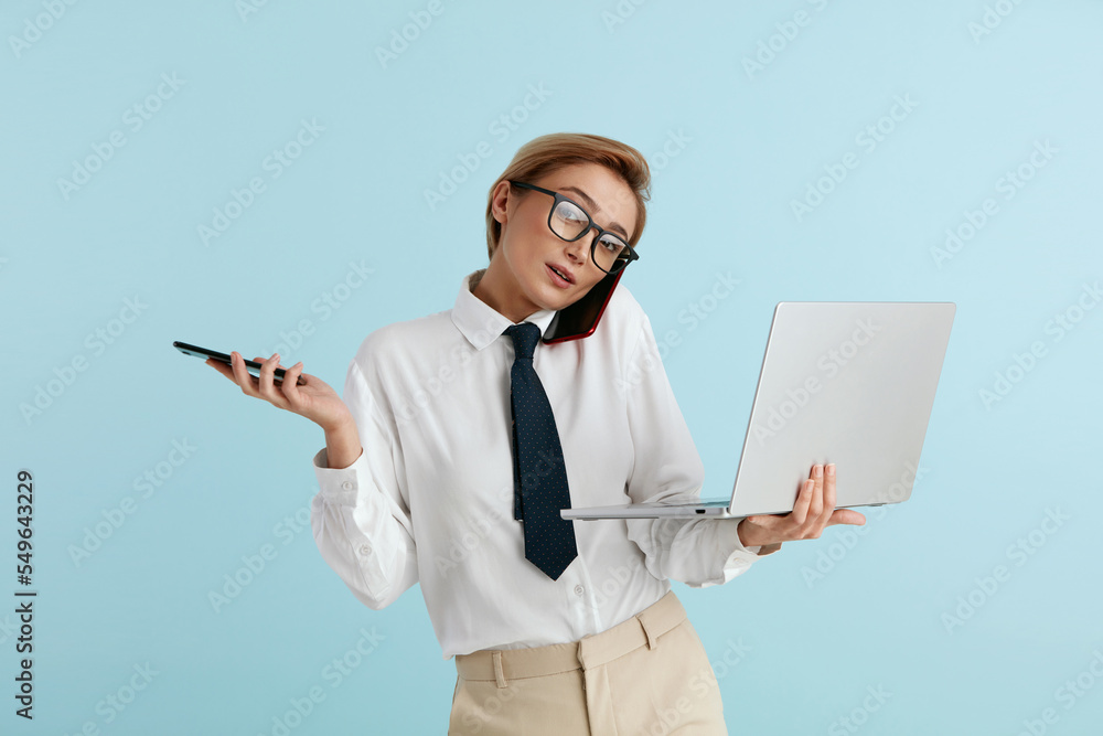 Busy Businesswoman Answering Calls Isolated. Caucasian Woman With Many Phones Feeling Stressful Holding Laptop. Lady Boss Talking Cellphone at Blue Background Busy Businesswoman Answering Calls Isolated. Caucasian Woman With Many Phones Feeling Stressful Holding Laptop. Lady Boss Talking Cellphone at Blue Background