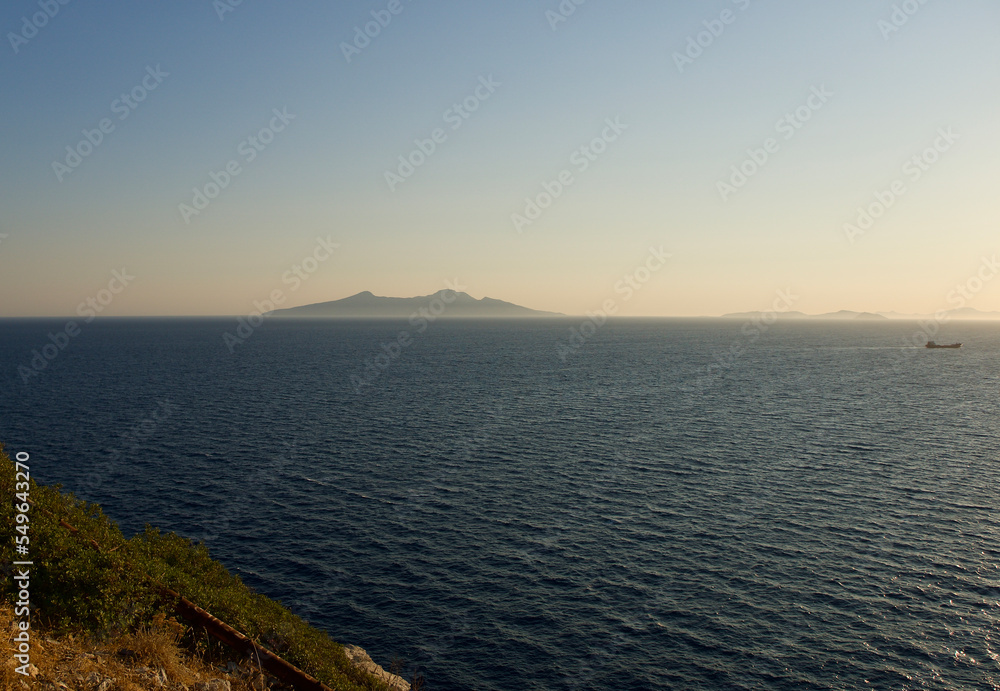 Aegean coast. Rocky and cliff seaside. Blue sky, dark blue sea and rocks. The focus is on the sea.