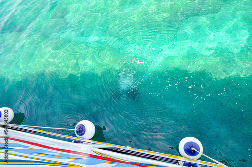 Fotografia turquoise sea water with a hull of the yacht and fenders
