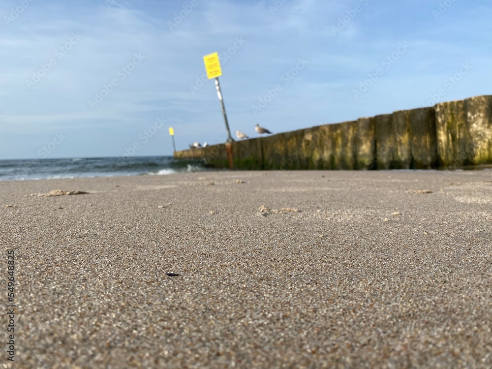 A wooden breakwater on the Baltic Sea, protecting the shore from the waves, a wide sandy beach A wooden breakwater on the Baltic Sea, protecting the shore from the waves, a wide sandy beach