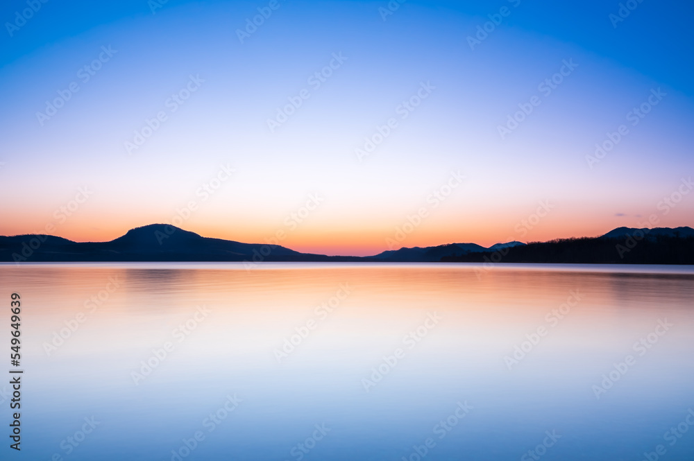 美しいグラデーションの空を反射する湖の風景。