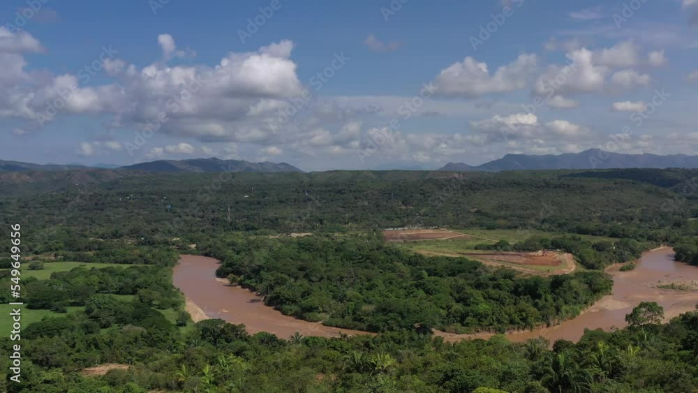 Aerial shot of mobile telephony antennas revelation, ending in a point of interest over the antennas, with beautiful river and mountains behind the antennas.